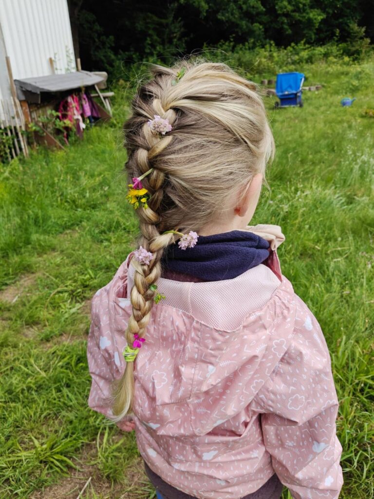 Mädchen mit geflochtenem Zopf auf einer Wiese
