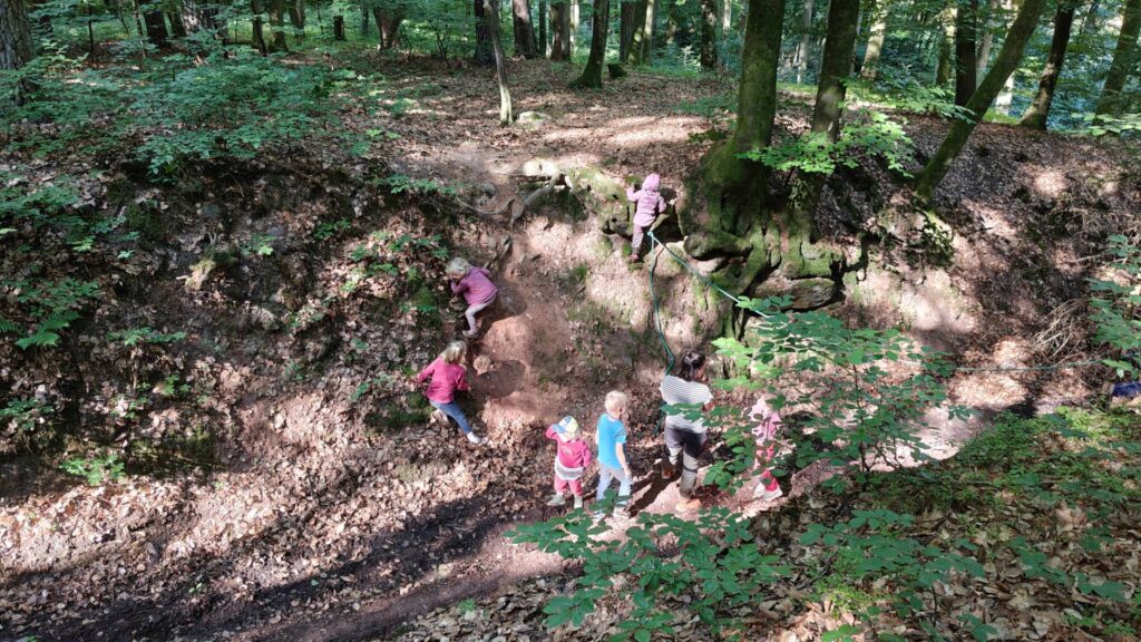 Kinder klettern in einer Waldschlucht im Spessart