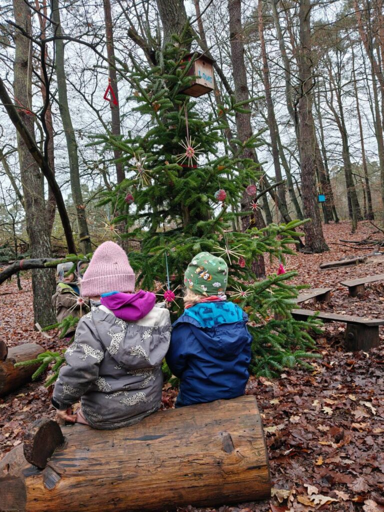 Zwei Kinder sitzen nebeneinander auf einem Baumstamm