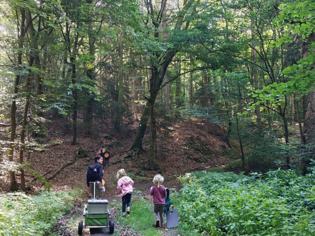 Kindergruppe mit Bollerwagen auf dem Weg ins Umland